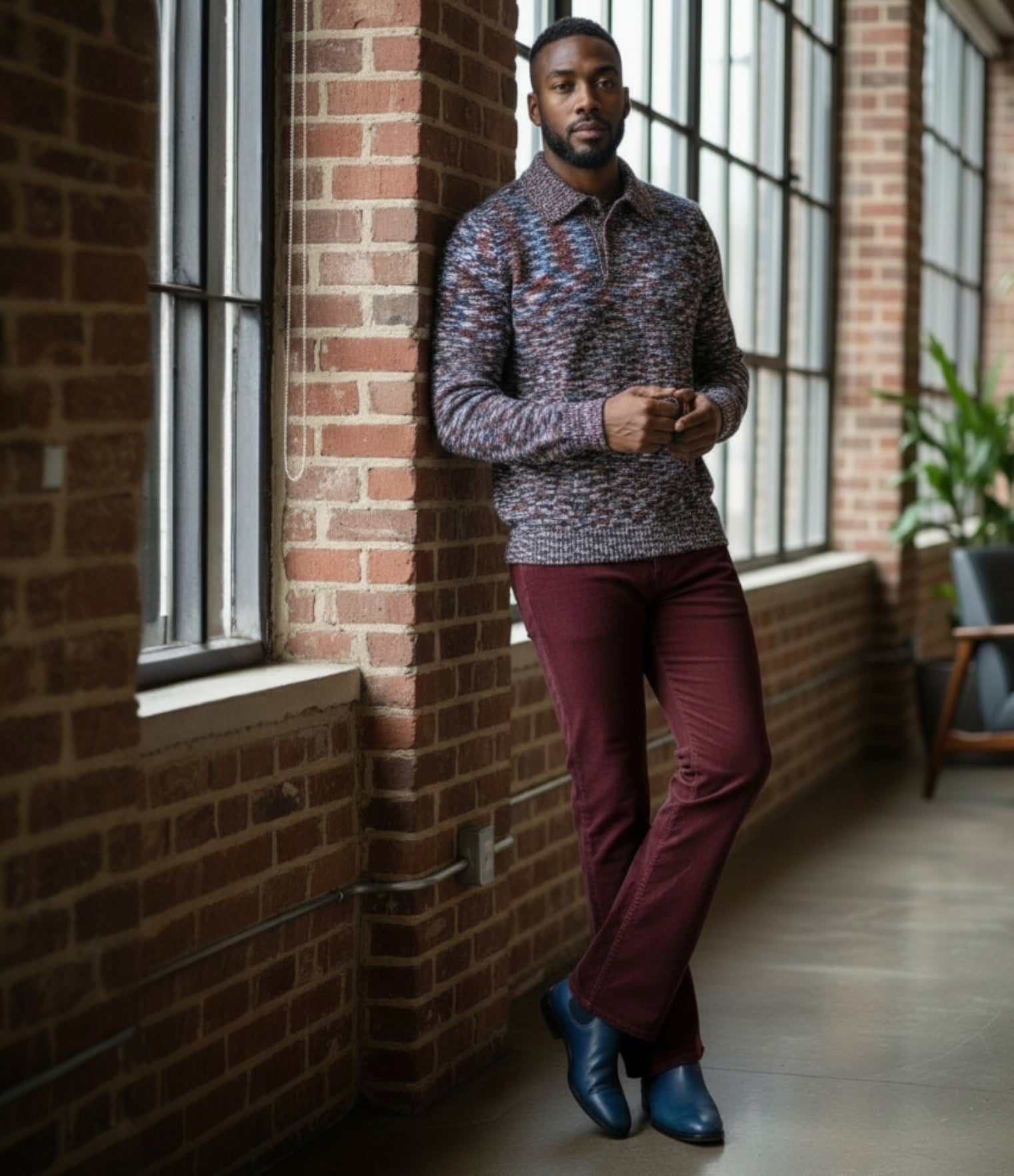 Man standing against a brick wall in a modern indoor setting