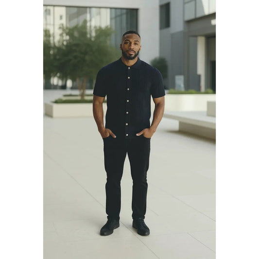 Man wearing a black button-up shirt and pants standing in an urban setting.