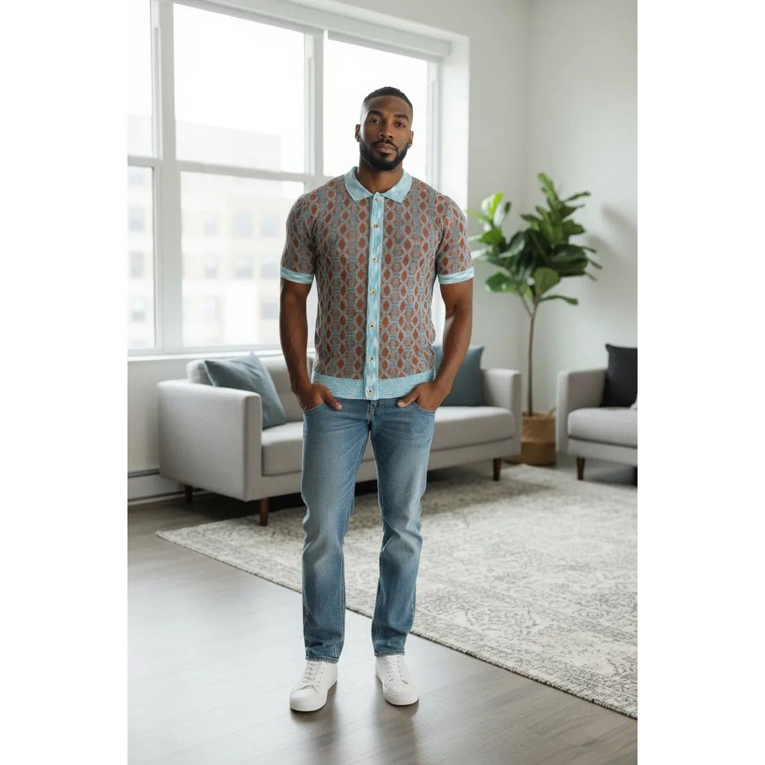 Man standing in a modern living room wearing a patterned shirt and jeans.