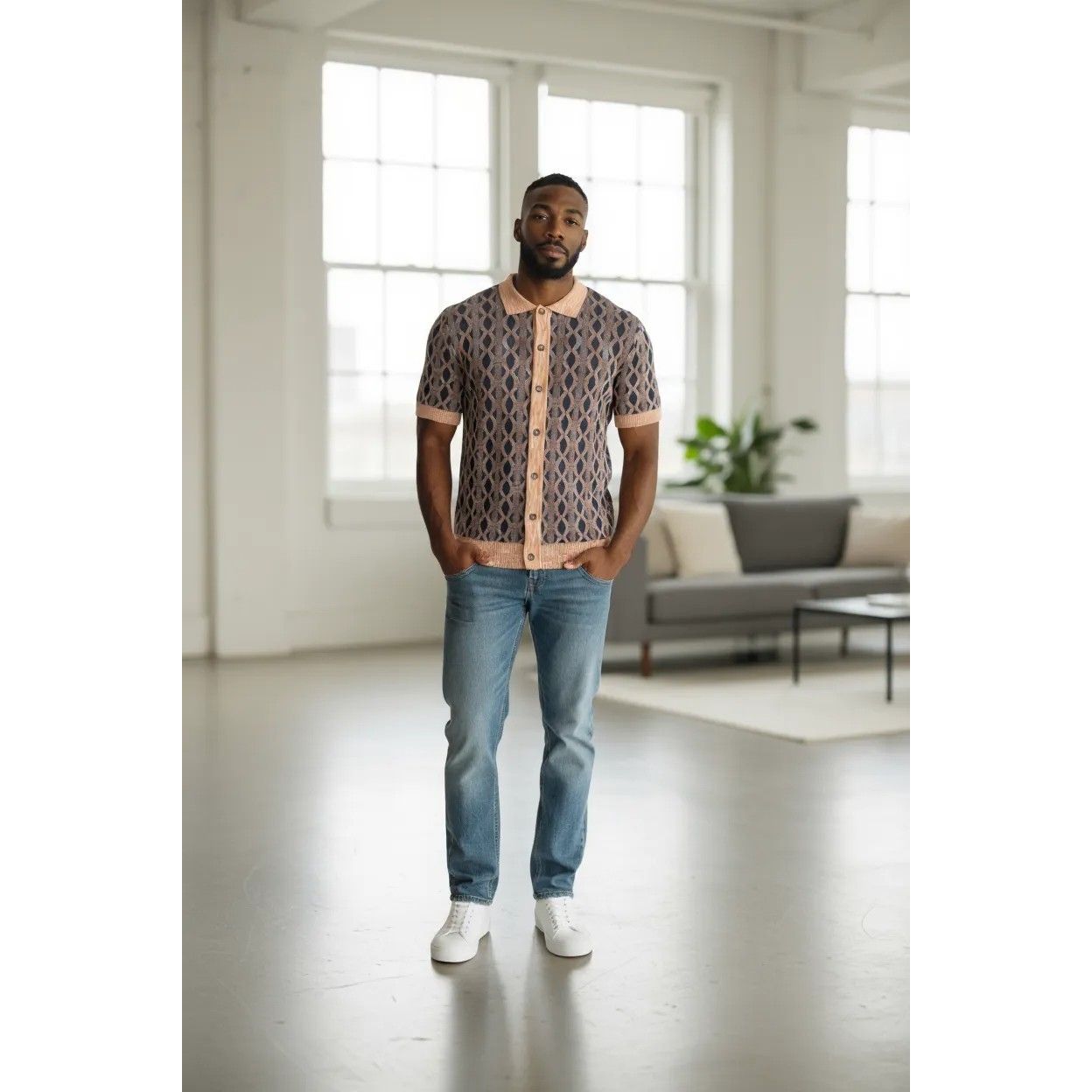Man wearing a patterned shirt and jeans standing in a modern living room.
