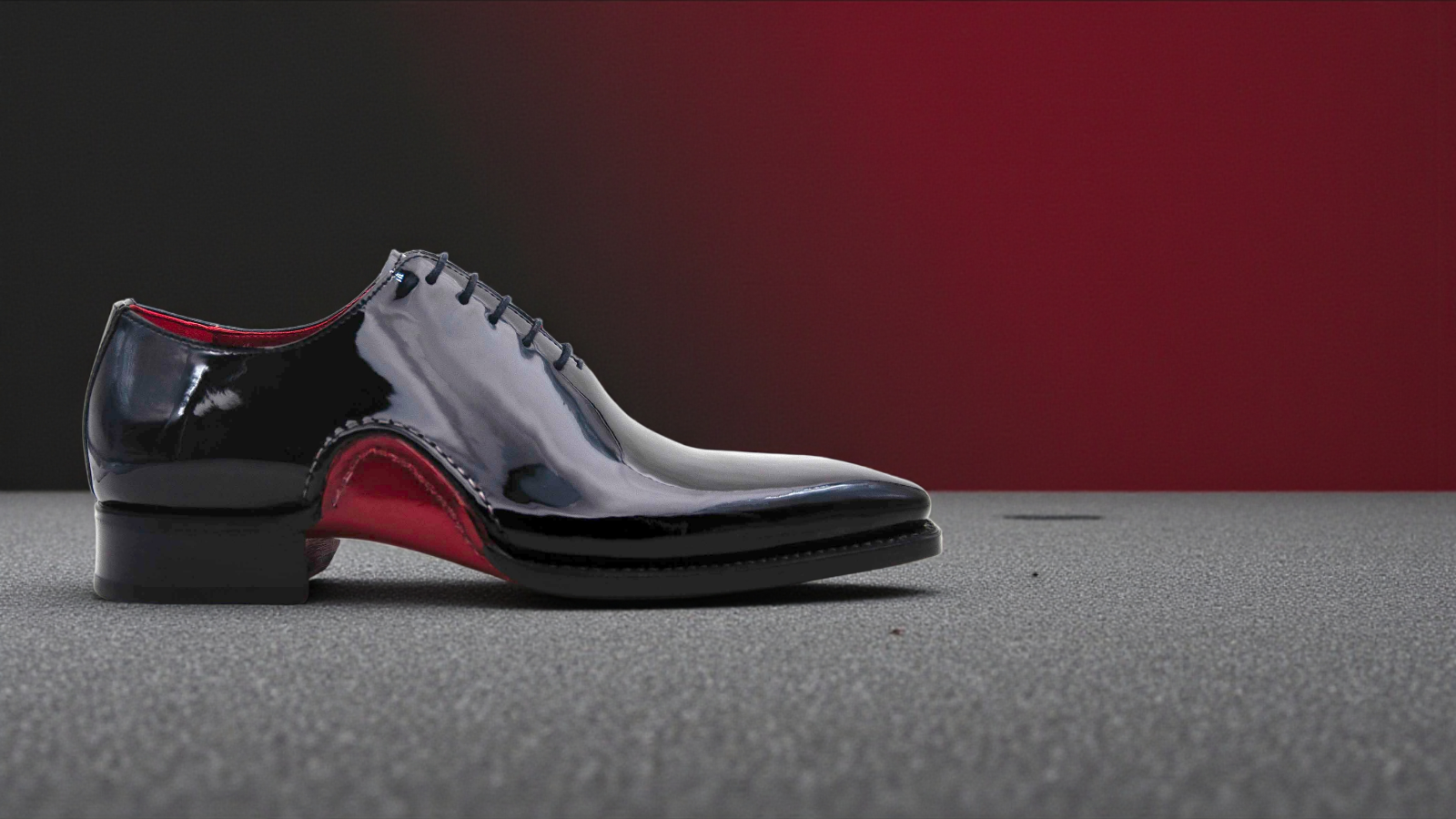Pair of black and white dress shoes with red soles on a dark surface.