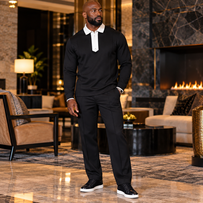 A man wearing a Suit Yourself Menswear black two-piece set with a white contrast quarter-zip collar in a luxury lounge.