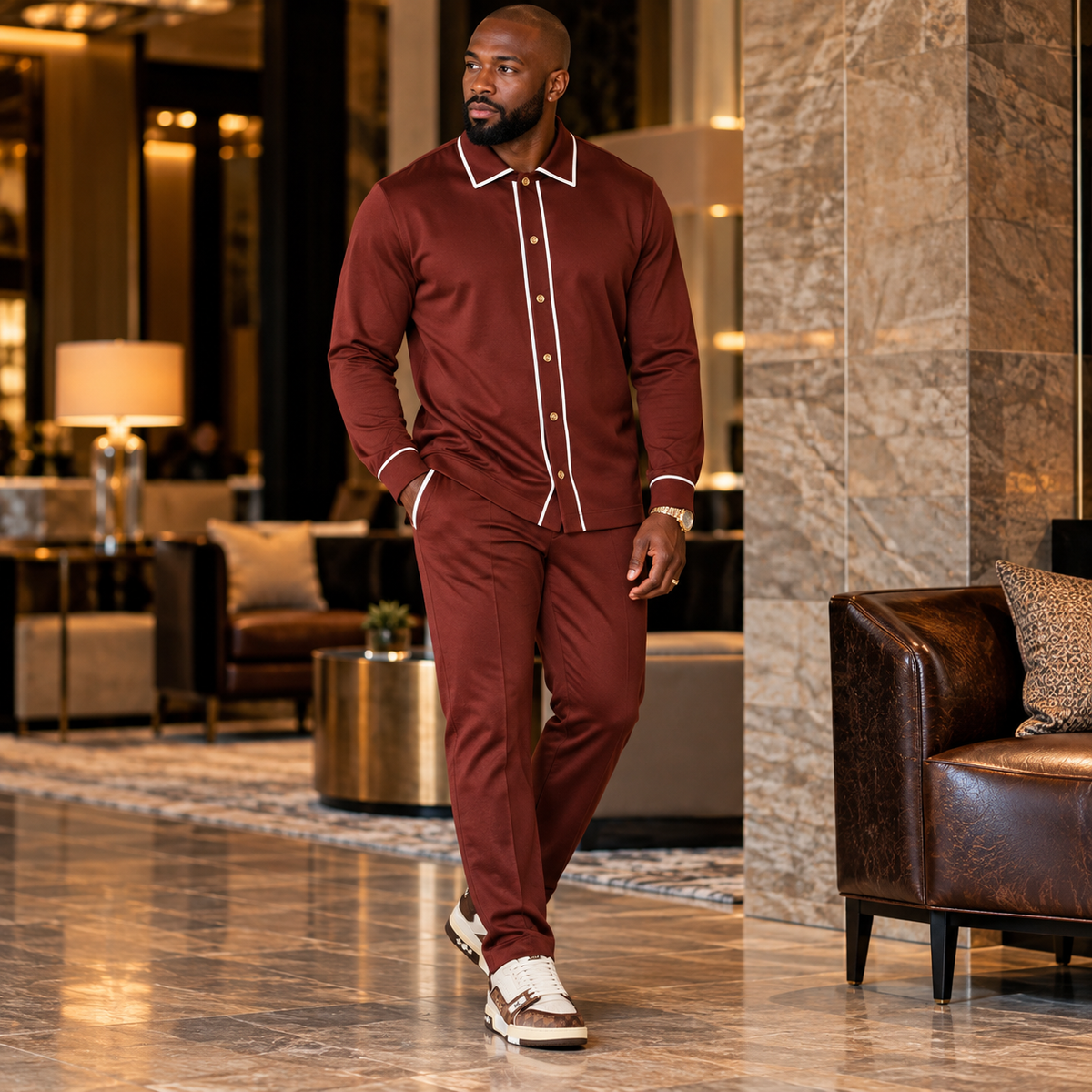 suit-yourself-menswear brown two-piece casual set with white contrast piping worn by a man in a luxury hotel lobby