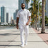 suit-yourself-menswear white lace linen two-piece casual set worn by a man walking on a sunny city waterfront promenade